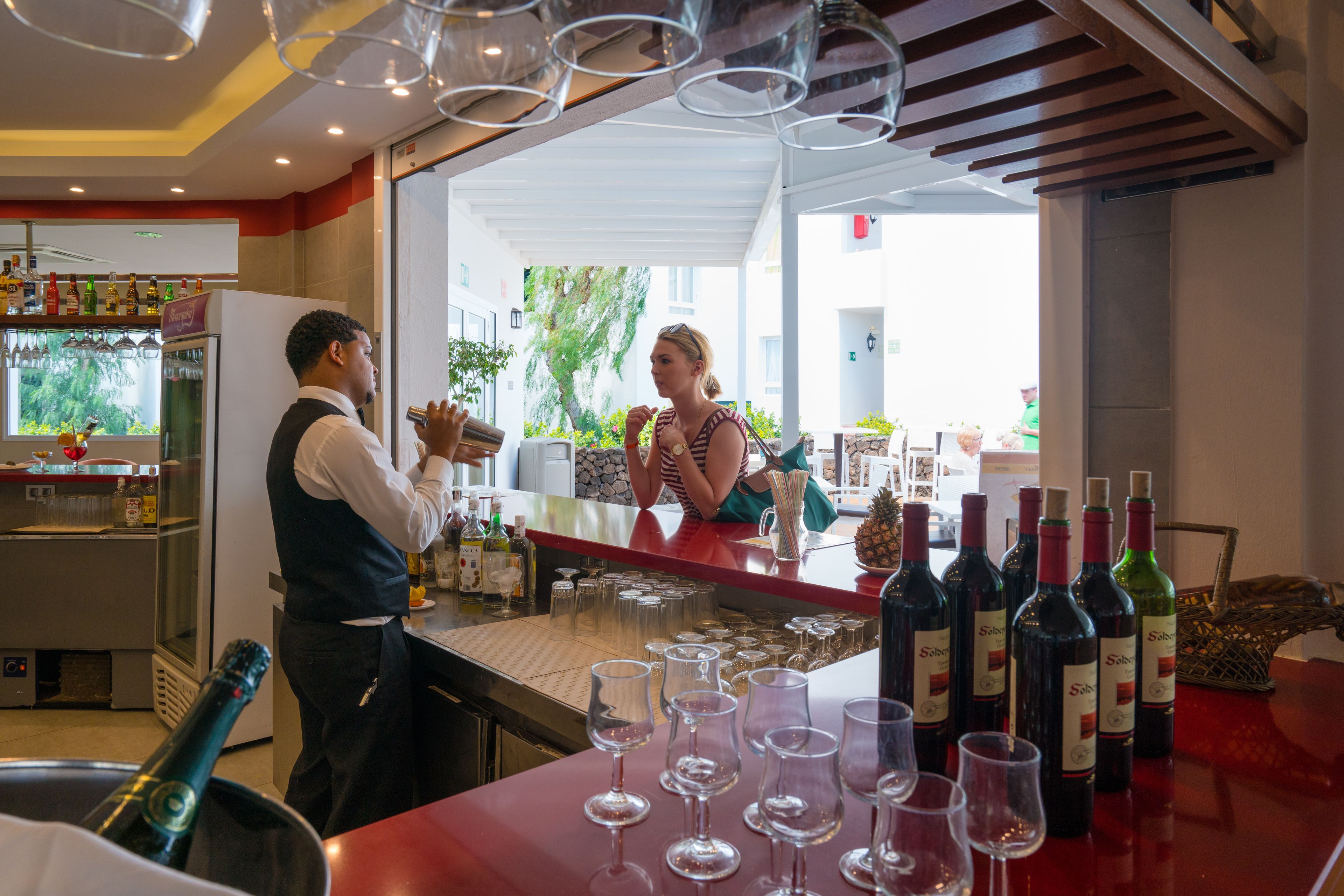 A bar area with a counter, wine bottles, and glasses.