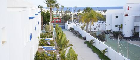 Un hotel costero con edificios blancos, una zona de piscina y vistas al mar.