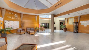 A spacious lobby with a high ceiling, wooden walls, and a central seating area with sofas and chairs. - Hotel Siroco - Adults Only (Teguise)