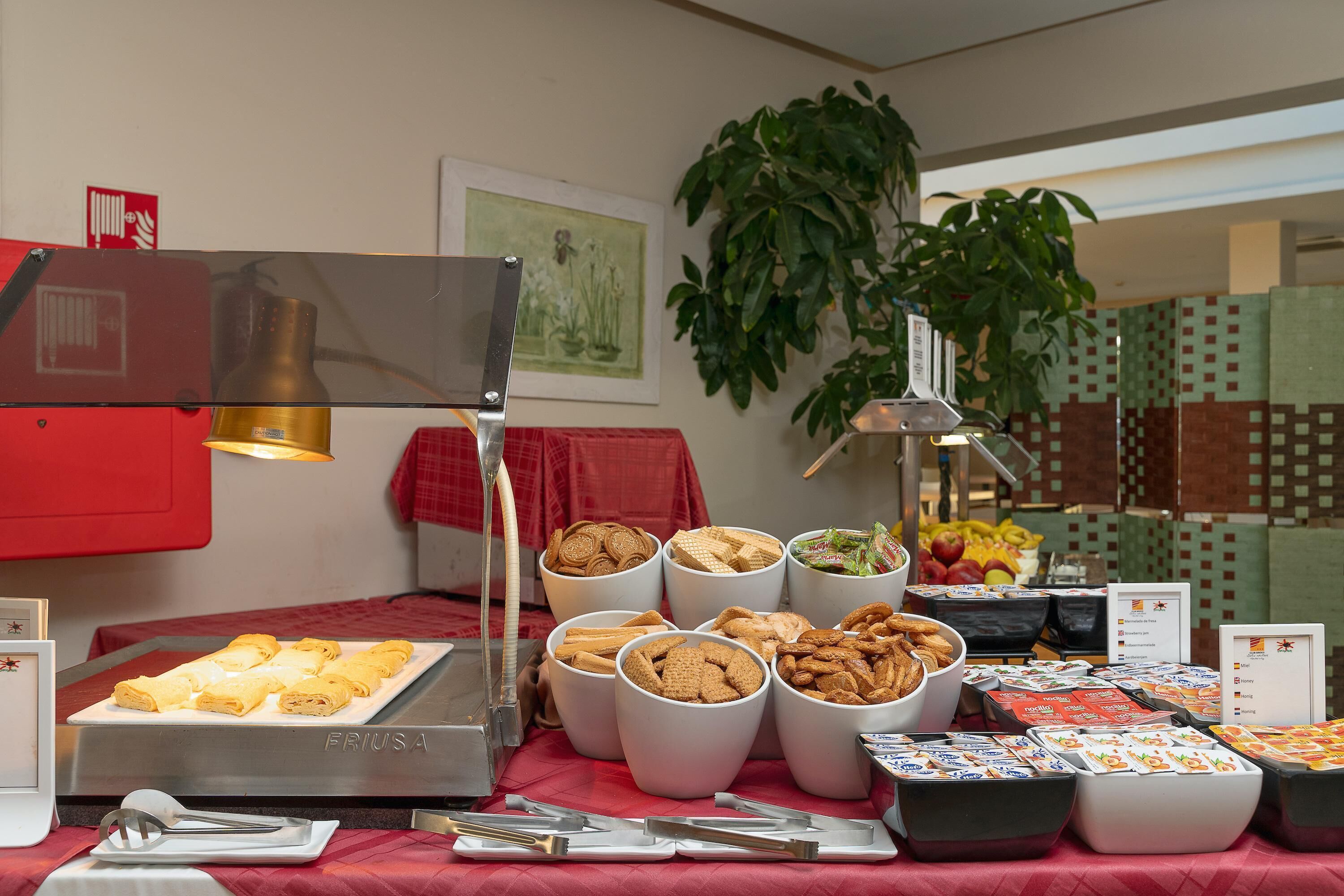 Un buffet proposant une variété de plats, notamment des pâtisseries et des salades, disposés sur une table recouverte d’une nappe rouge.