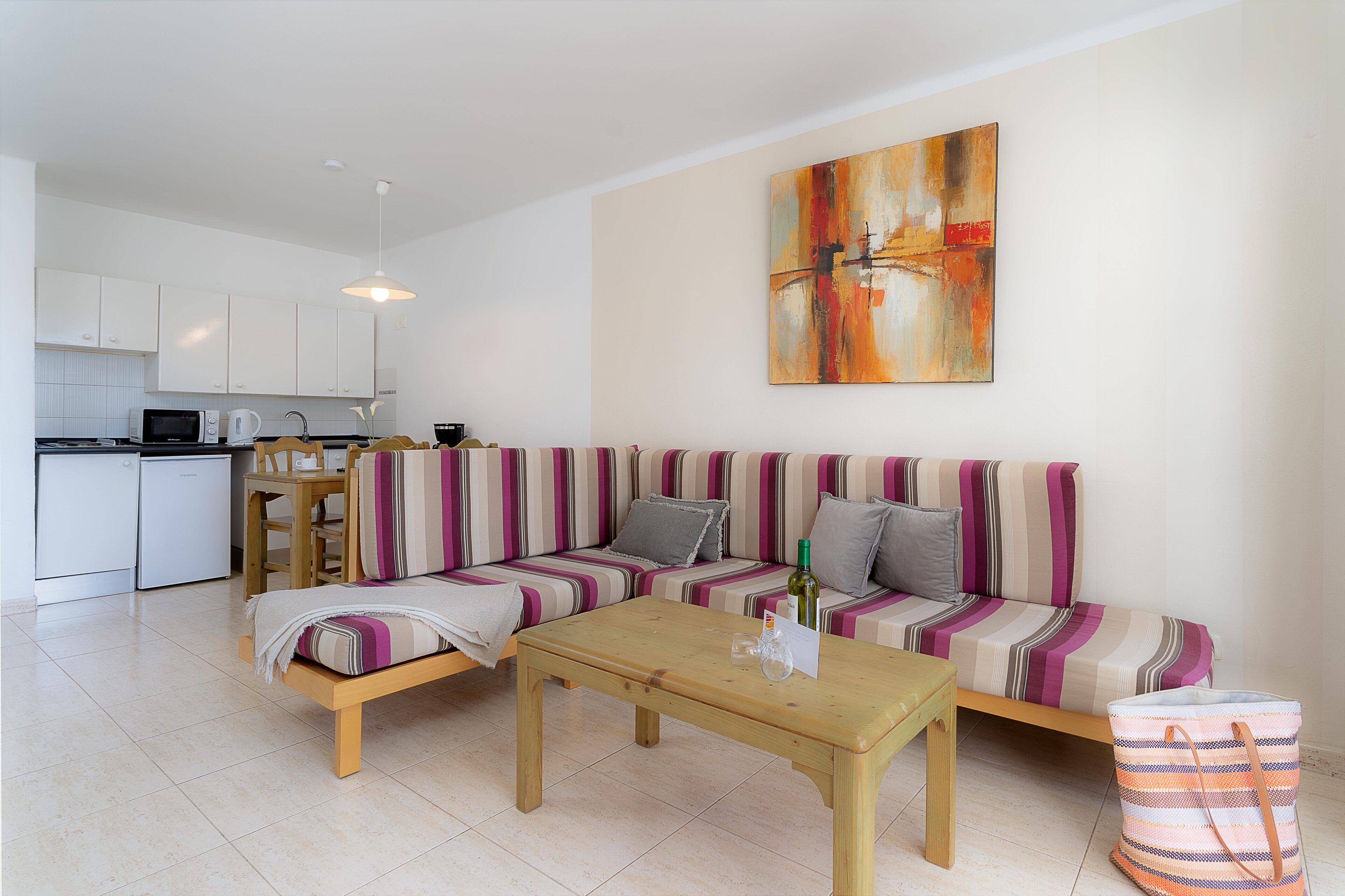 A modern living room with a sofa, a coffee table, and a kitchen in the background.