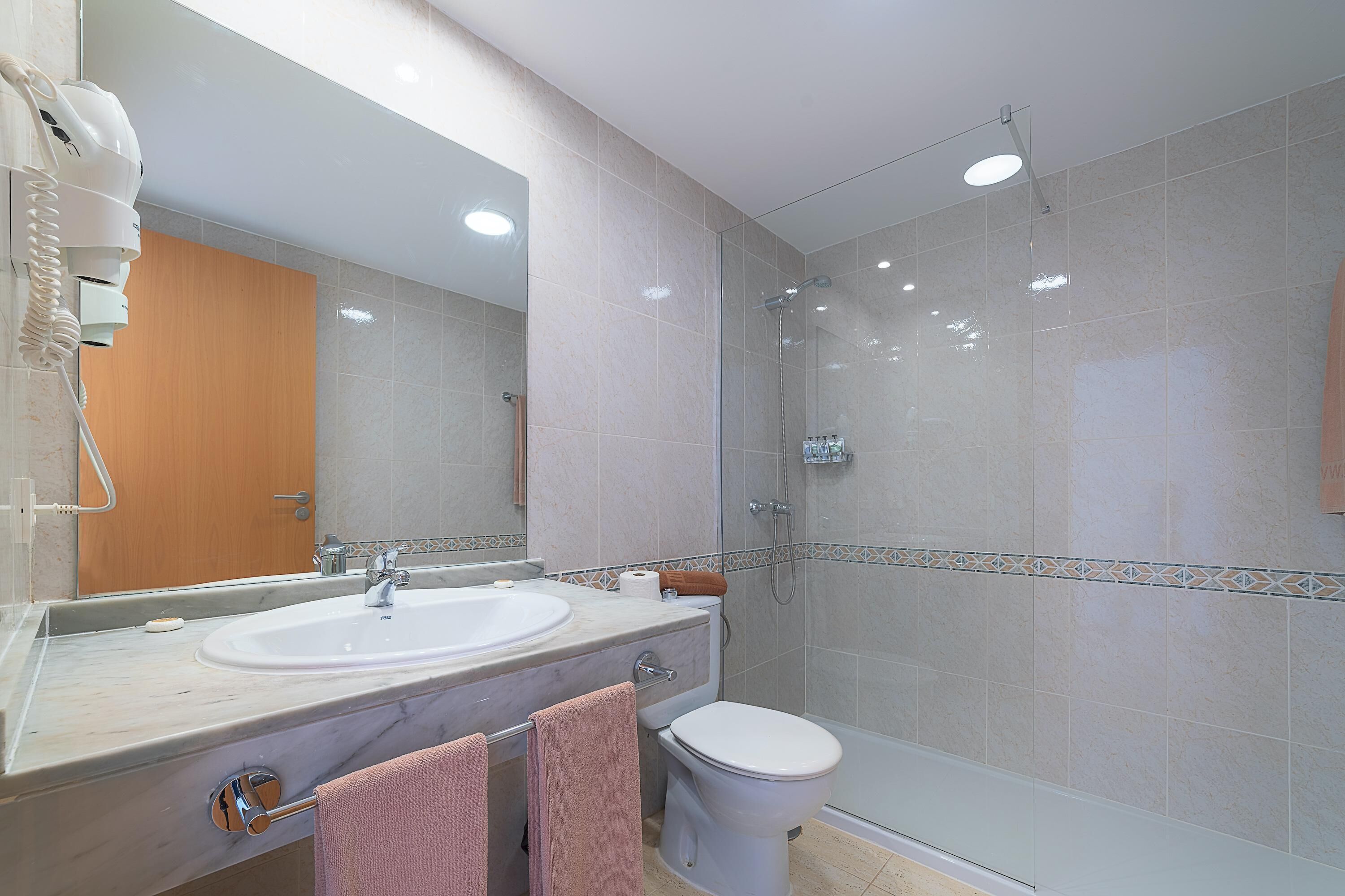 Un baño moderno con lavamanos, espejo e inodoro.
