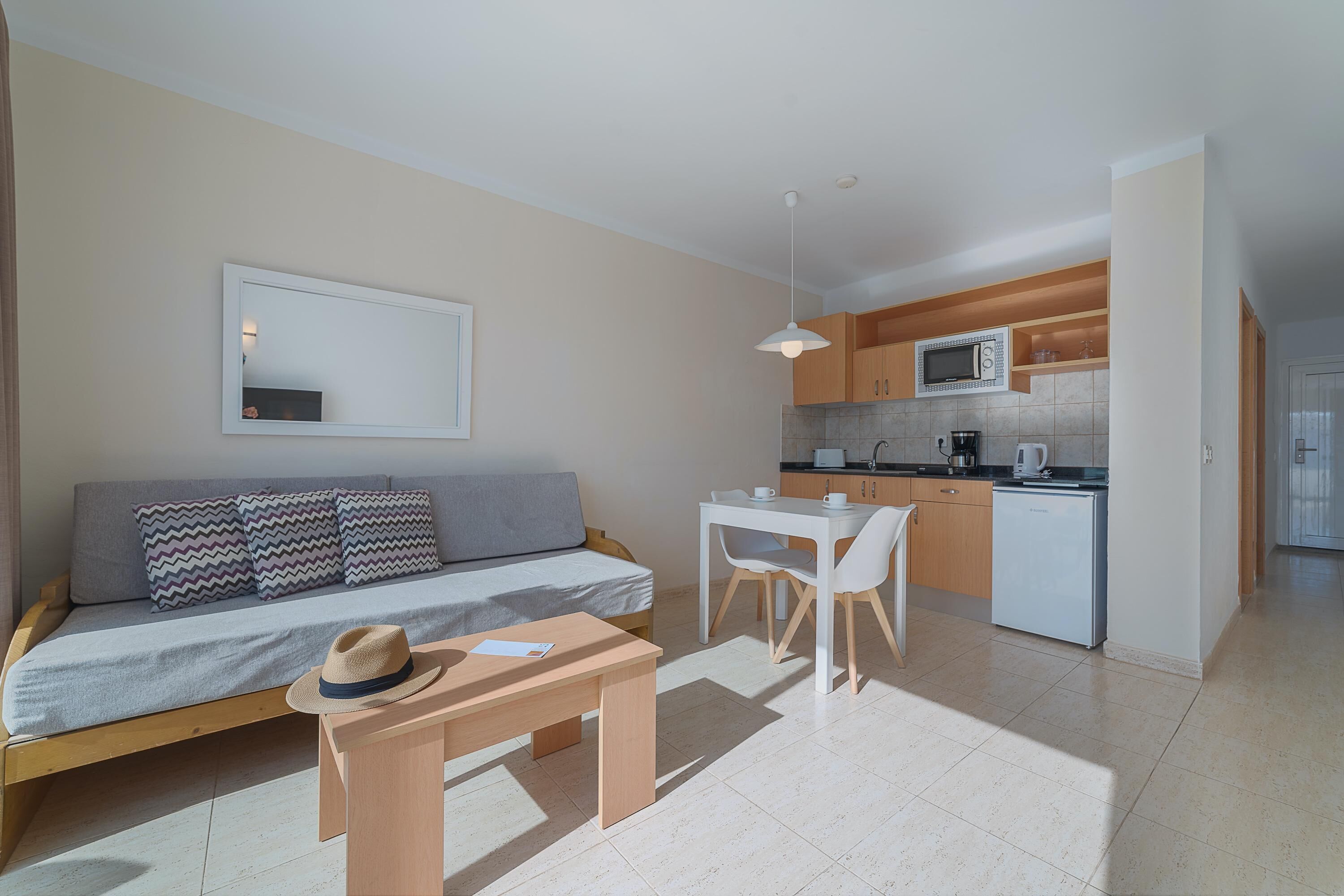 A compact living space with a sofa, a dining table, and a kitchenette.
