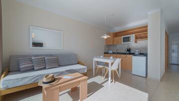 A compact living space with a sofa, a dining table, and a kitchenette.