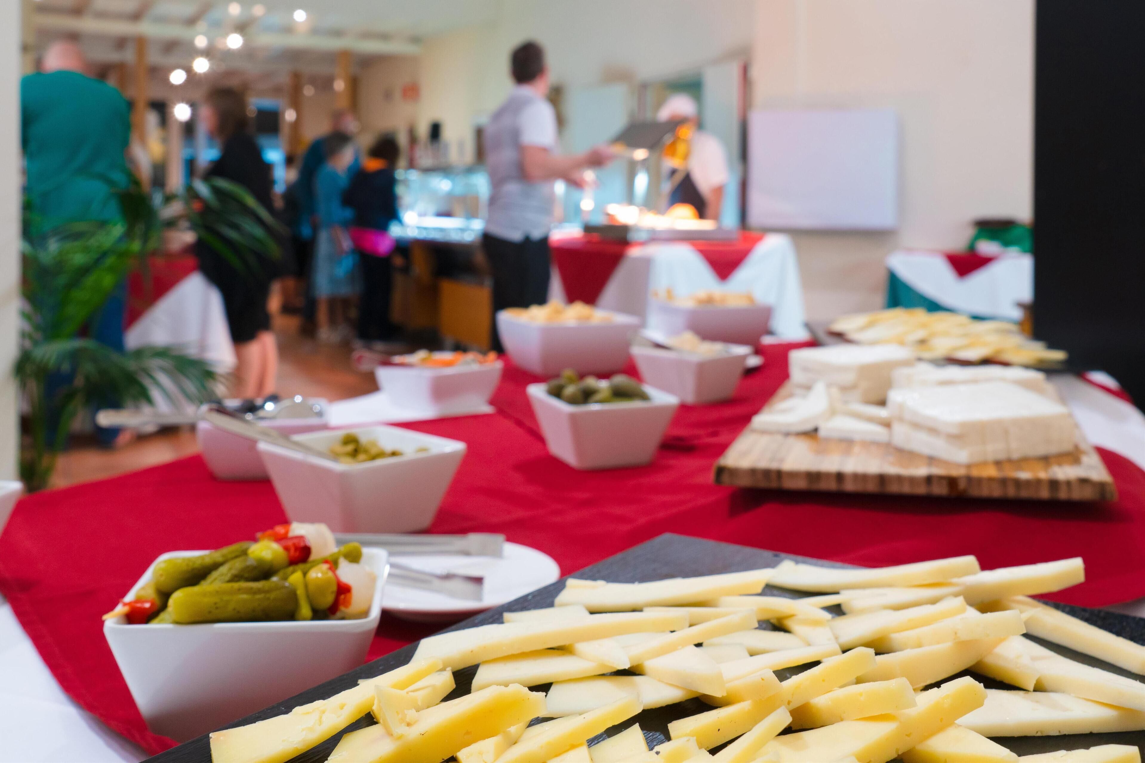 Una taula de buffet amb diversos aliments, com ara formatge, pickles i pa.
