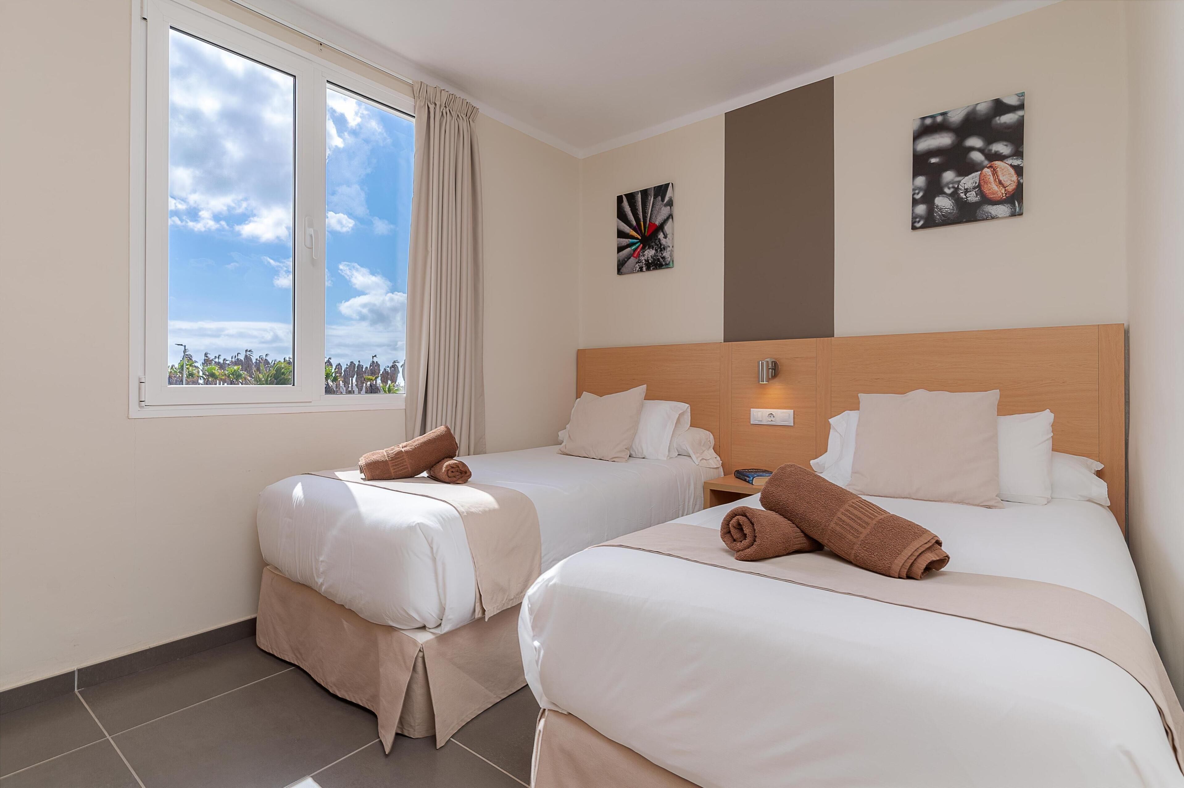 Una habitación de hotel con dos camas, un ventanal con vistas y obras de arte en las paredes.