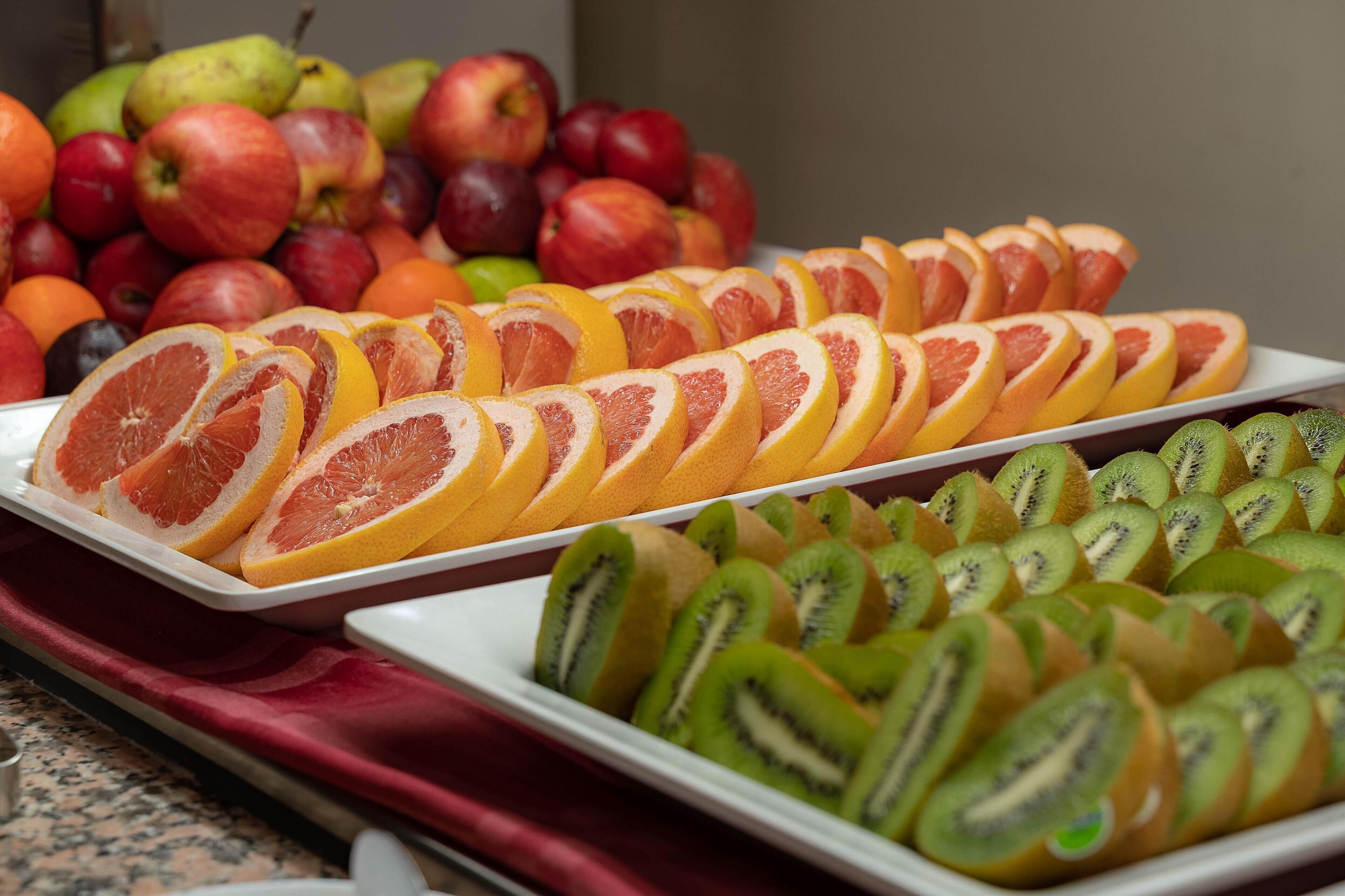 A variety of fruits including sliced oranges, kiwis, and apples arranged on trays.