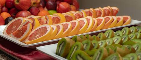A variety of fruits including sliced oranges, kiwis, and apples arranged on trays.