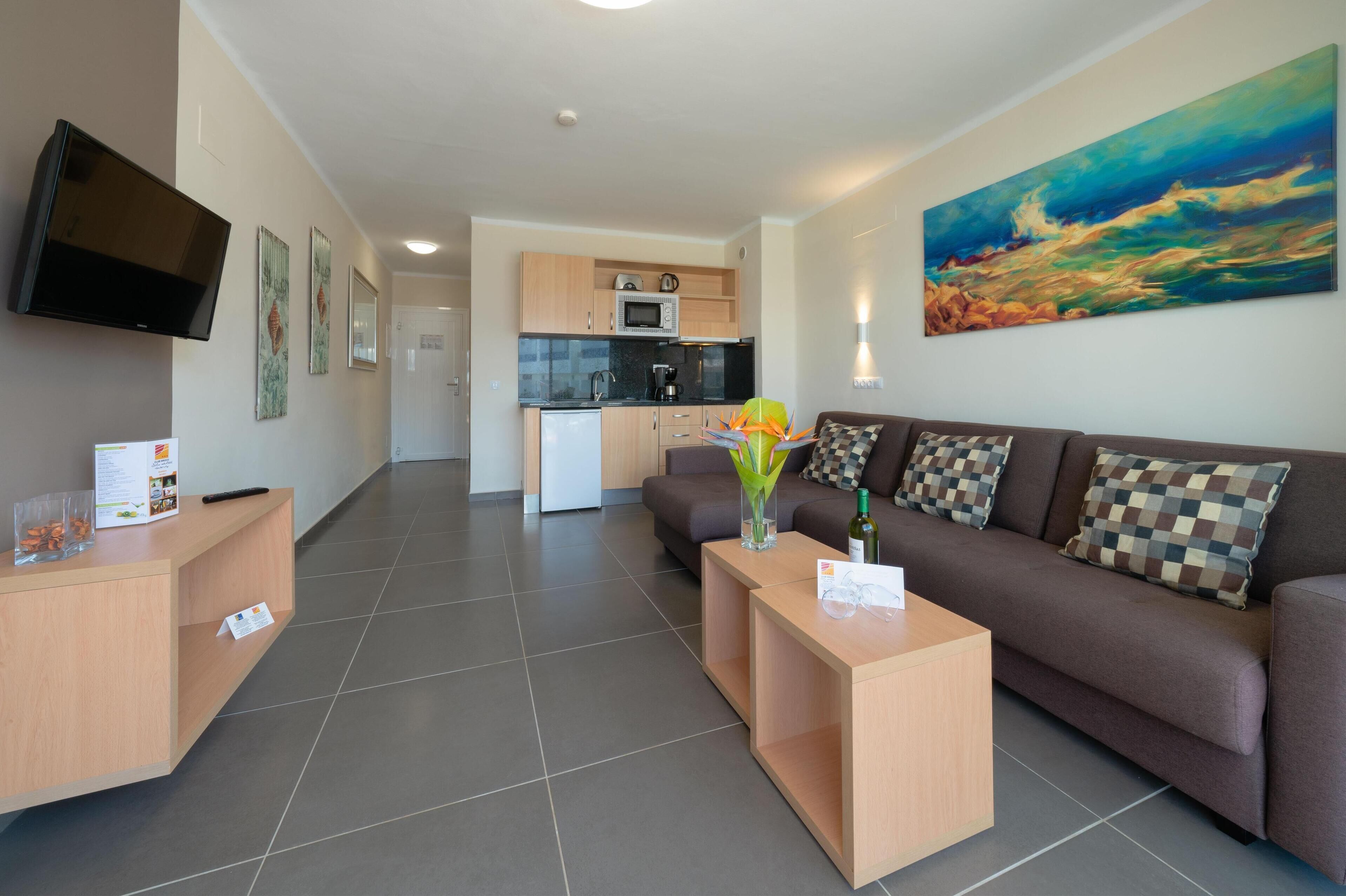 A modern living room with a sofa, coffee table, and a flat-screen TV mounted on the wall.