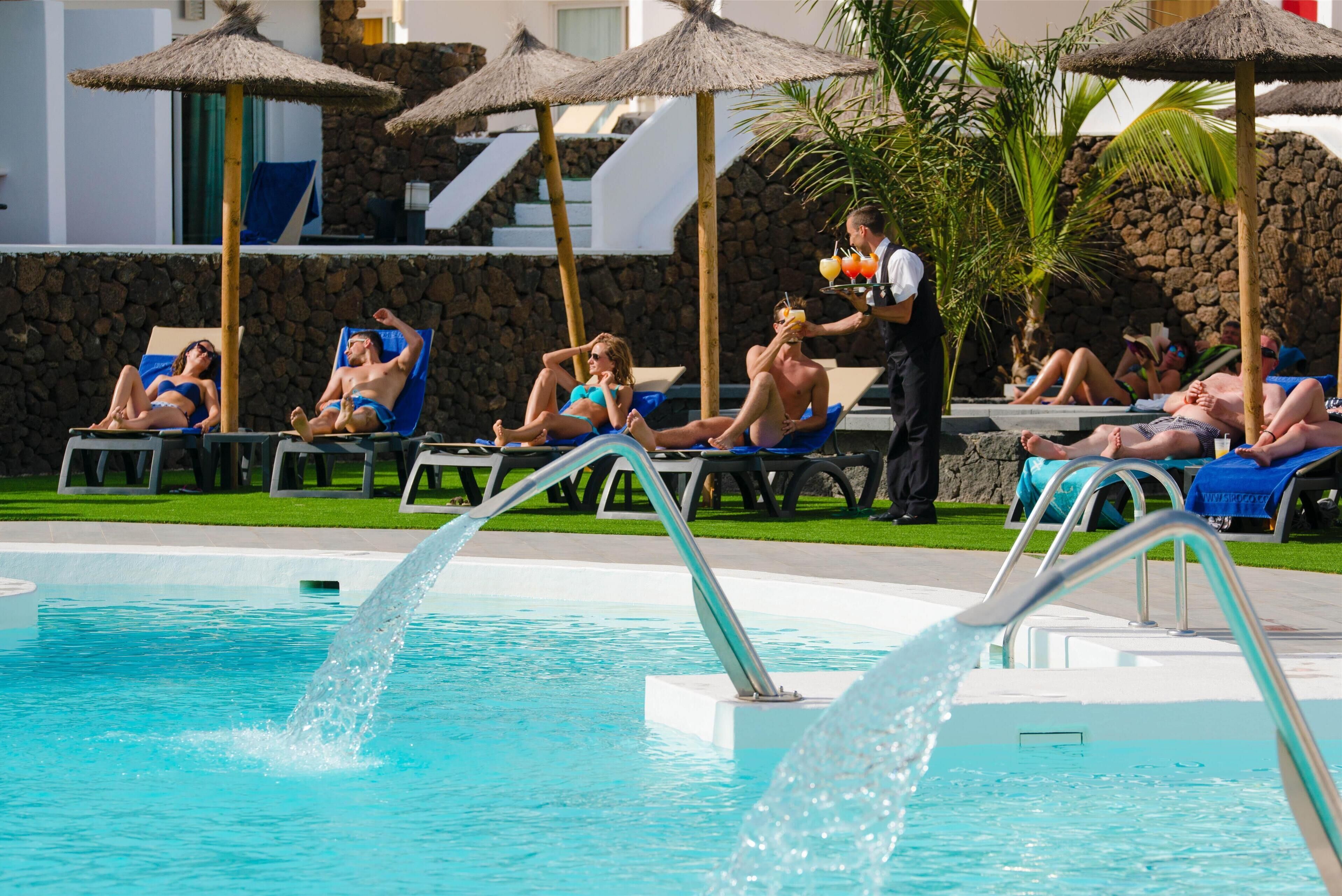 A pool area with lounge chairs and umbrellas.