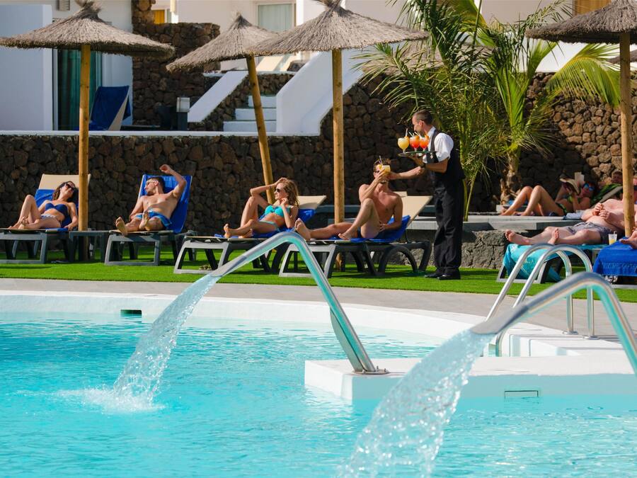 A pool area with lounge chairs and umbrellas.
