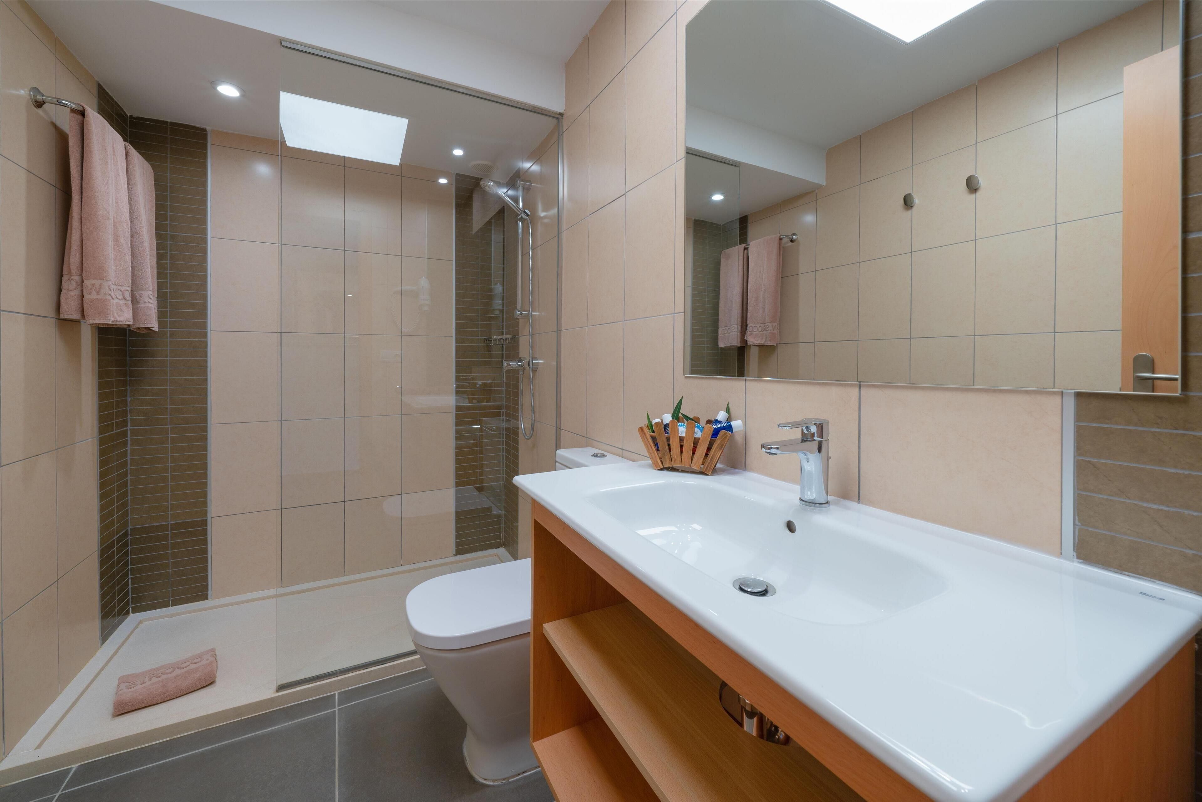 A modern bathroom with a glass shower enclosure, a white sink, and a toilet.