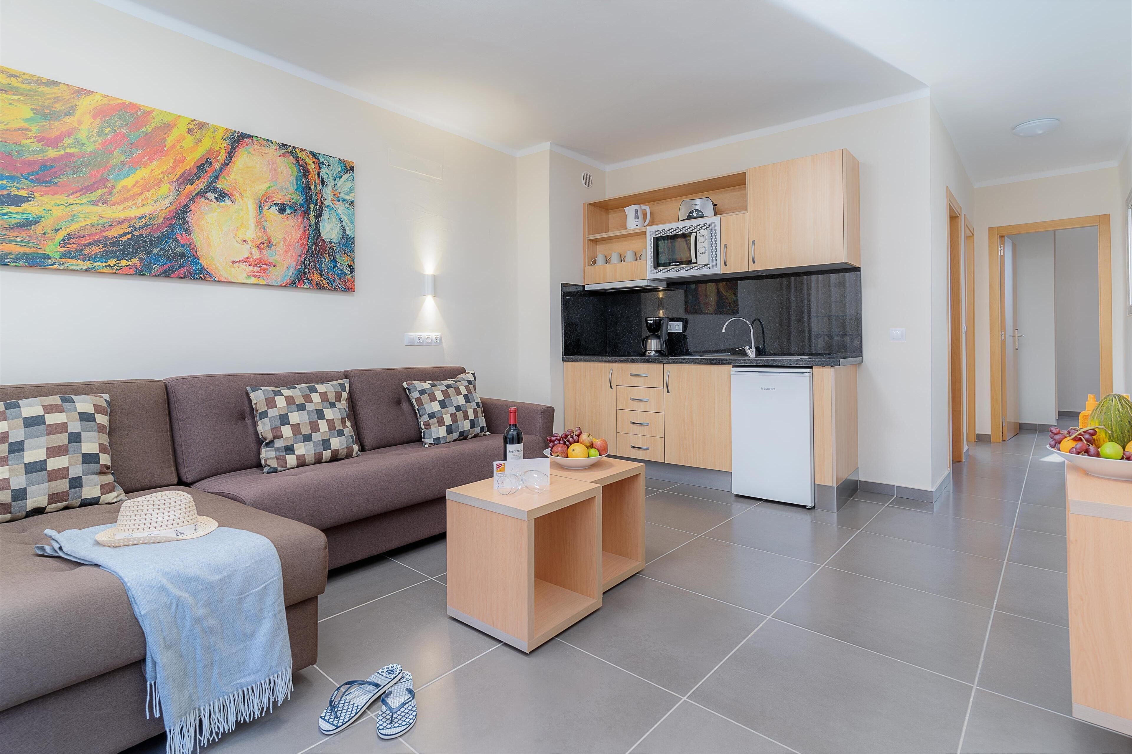 A modern apartment with a living area, kitchenette, and a dining space.