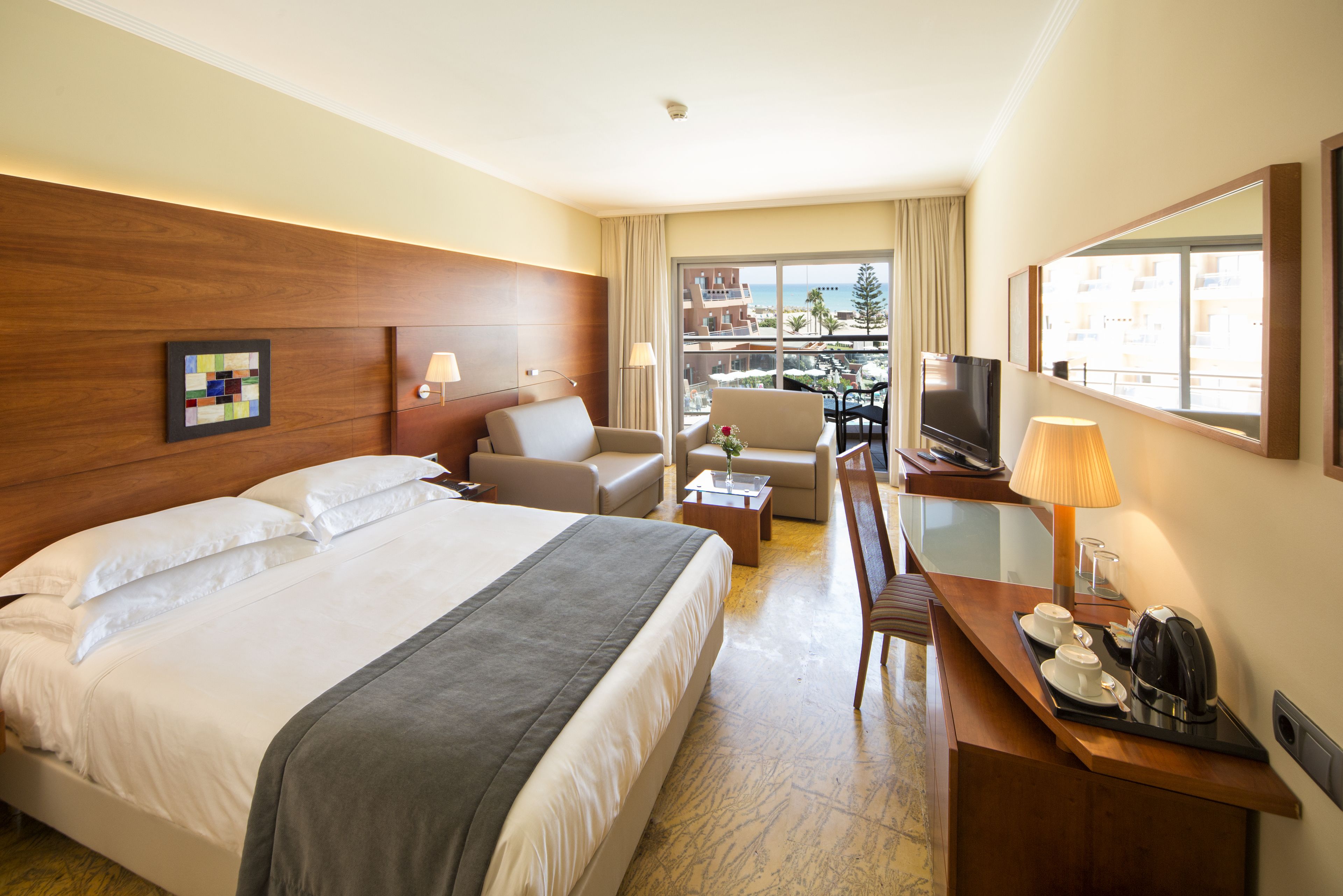 Une chambre d’hôtel avec un grand lit, un bureau avec une lampe, une chaise et un téléviseur.