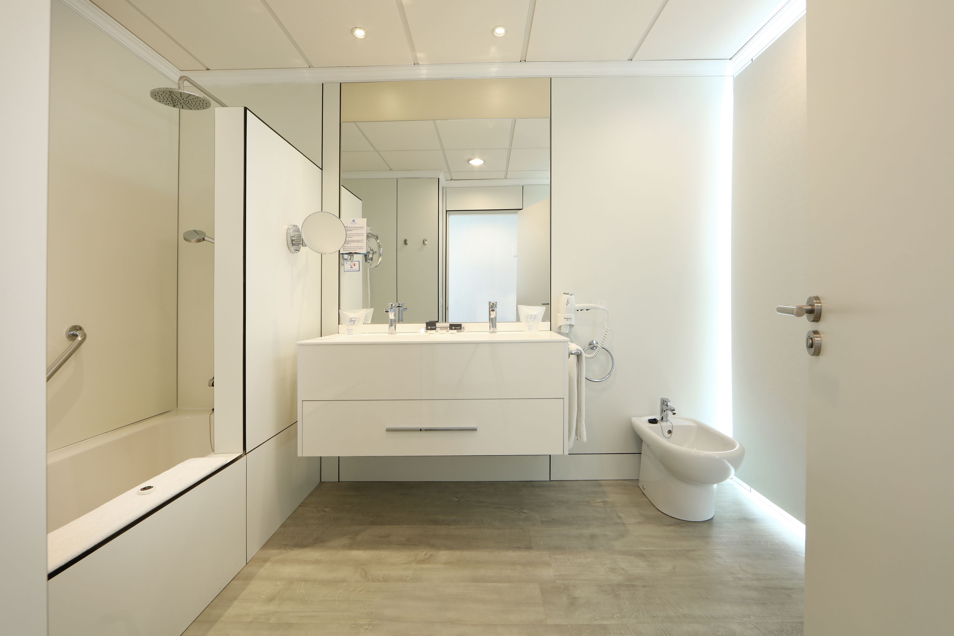 Une salle de bain moderne équipée d’une douche, d’un bidet, d’un lavabo avec un miroir et de toilettes.