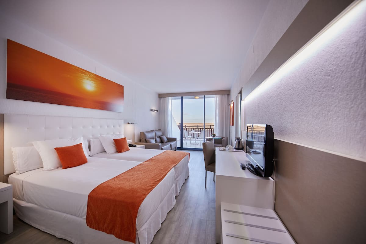A modern hotel room with a large bed, a desk, and a TV.
