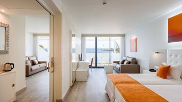 Een moderne hotelkamer met een groot bed, een bank, een bureau en uitzicht op de oceaan.