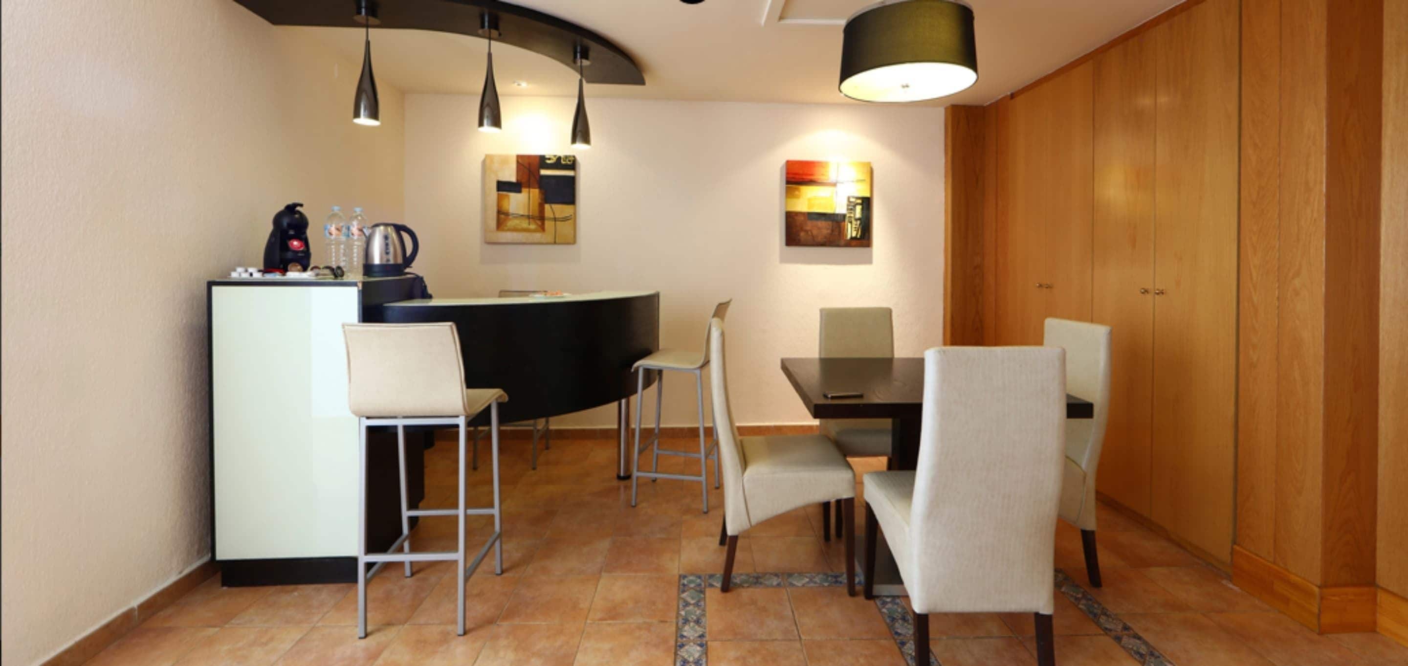 A modern kitchen with a central island, bar stools, and pendant lighting.