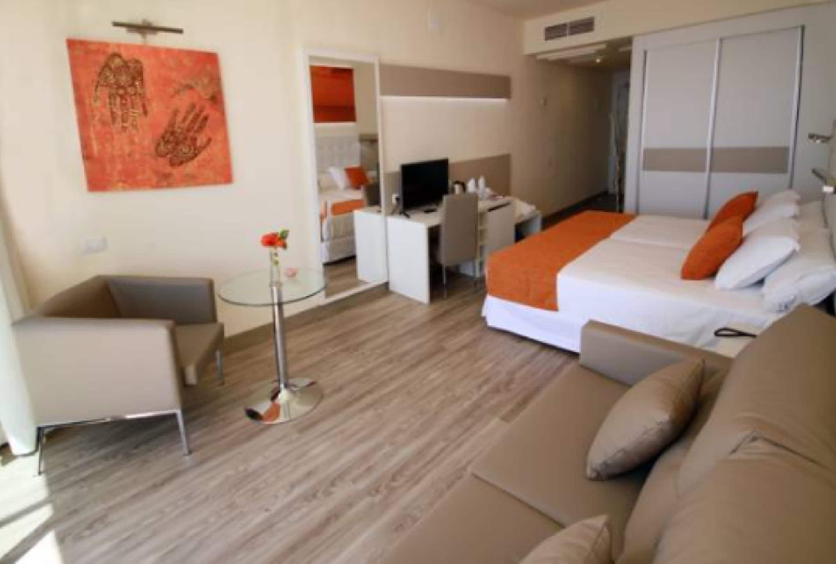 Une chambre d’hôtel équipée d’un lit, d’un bureau, d’une chaise, d’une télévision et d’une armoire.