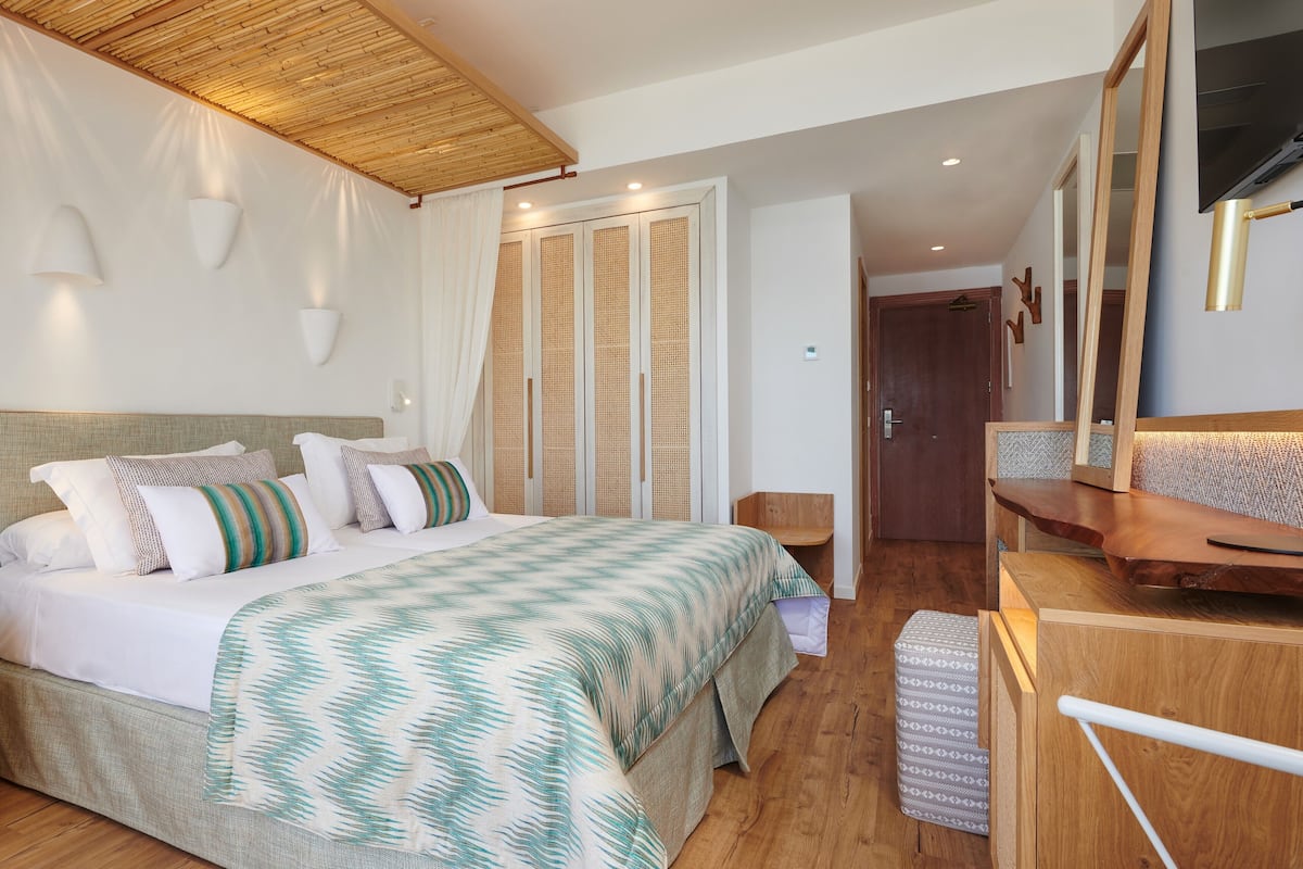 Een slaapkamer met een bed, nachtkastjes, een kledingkast, een spiegel en een plafond met een houten balk.