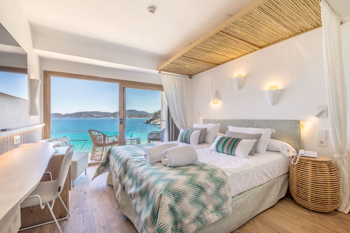 Een slaapkamer met een groot bed, een bureau en uitzicht op zee.