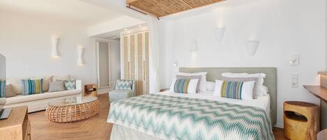 A modern bedroom with a large bed, a sofa, and a wicker coffee table.