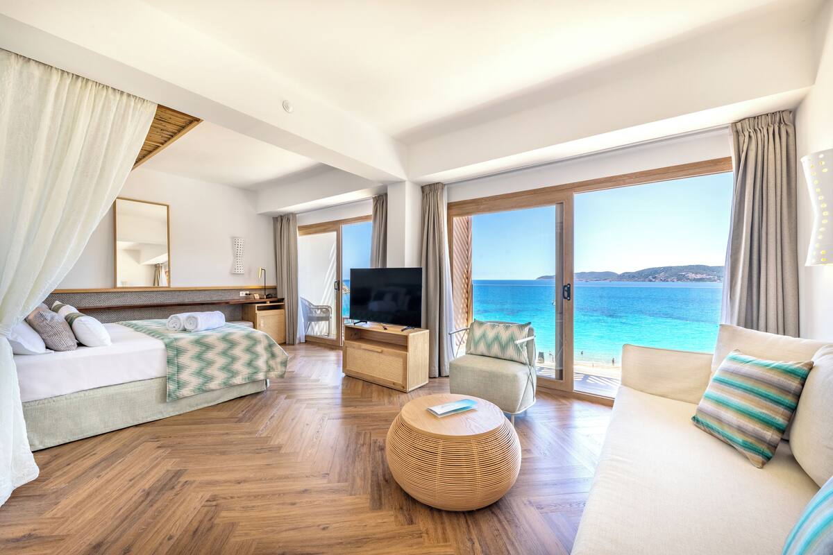 Een ruime kamer met een groot bed, een bank, een televisie en uitzicht op zee.