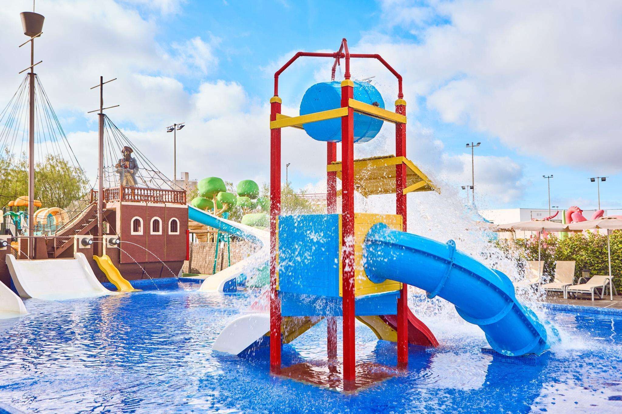 A water park with a pirate-themed play structure, slides, and a pool.