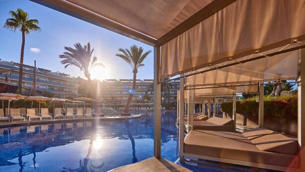 Zona de piscina con sillones de descanso y vista al agua.
