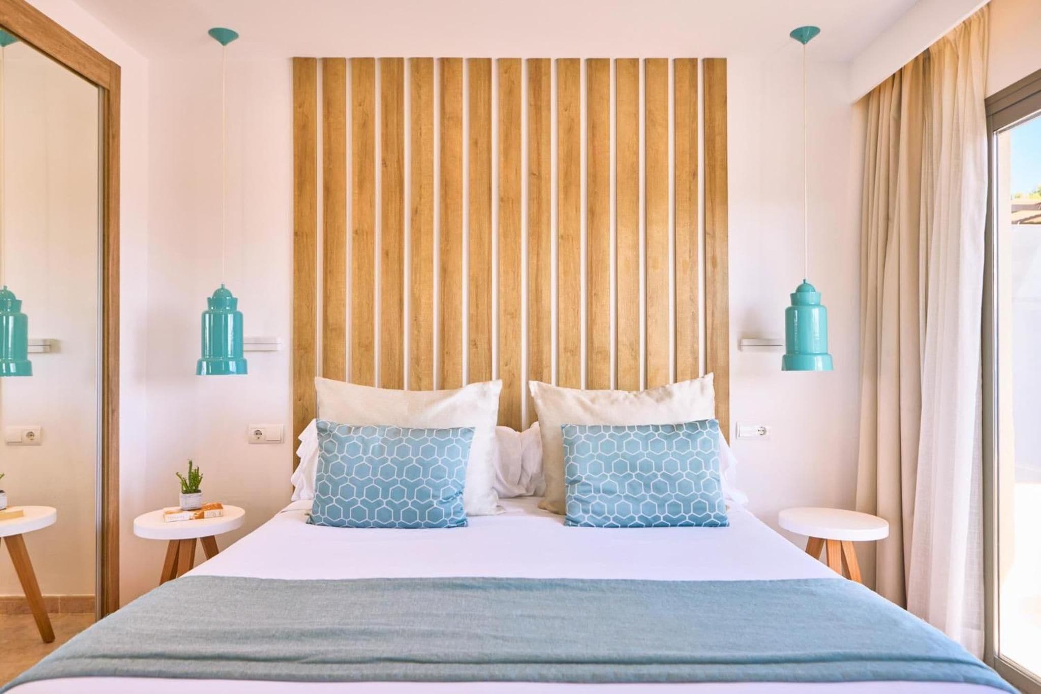 A hotel room with a bed, two bedside tables, a wooden slat wall, and two wall-mounted lamps.