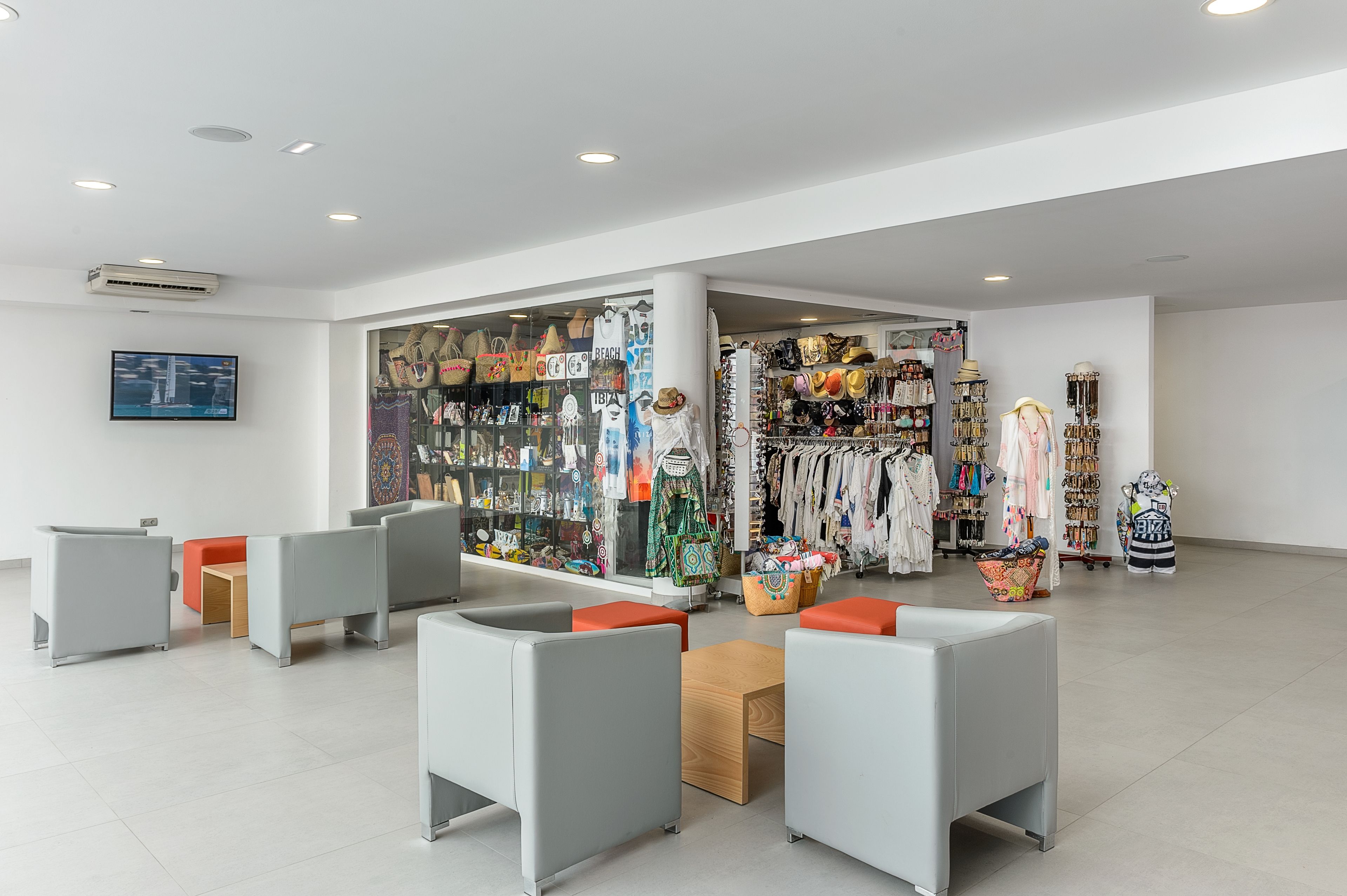 A modern interior with seating areas, a display of bags, and a television.