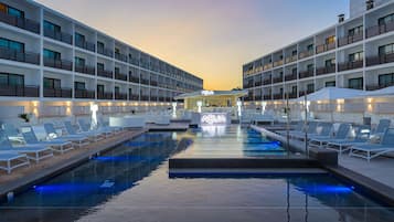 Una piscina al aire libre, sombrillas, sillones reclinables de piscina