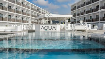 Una piscina al aire libre, sombrillas, sillones reclinables de piscina