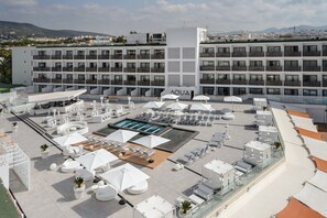 Una piscina al aire libre, sombrillas, sillones reclinables de piscina