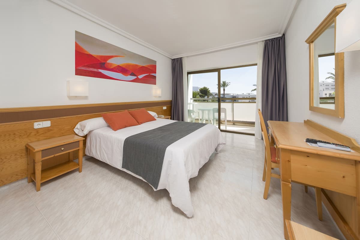 Una habitación de hotel con cama, escritorio y vistas al exterior.