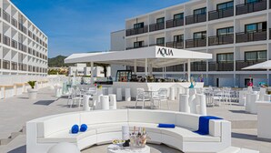 A modern outdoor seating area with white furniture and a bar area with a sign reading "AQUA". - Hotel Vibra Mare Nostrum (Ibiza Town)