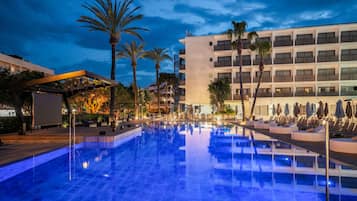 Una piscina al aire libre, sombrillas, sillones reclinables de piscina