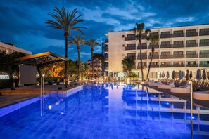 A swimming pool with lounge chairs and umbrellas, surrounded by palm trees and a multi-story building. - Hotel Vibra Mare Nostrum (Ibiza Town)