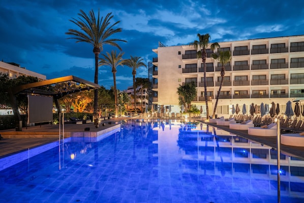 Una piscina al aire libre, sombrillas, sillones reclinables de piscina