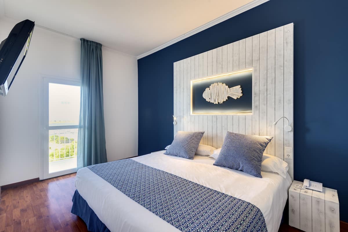 A modern bedroom with a large bed, a wooden headboard, and a view of the outdoors.
