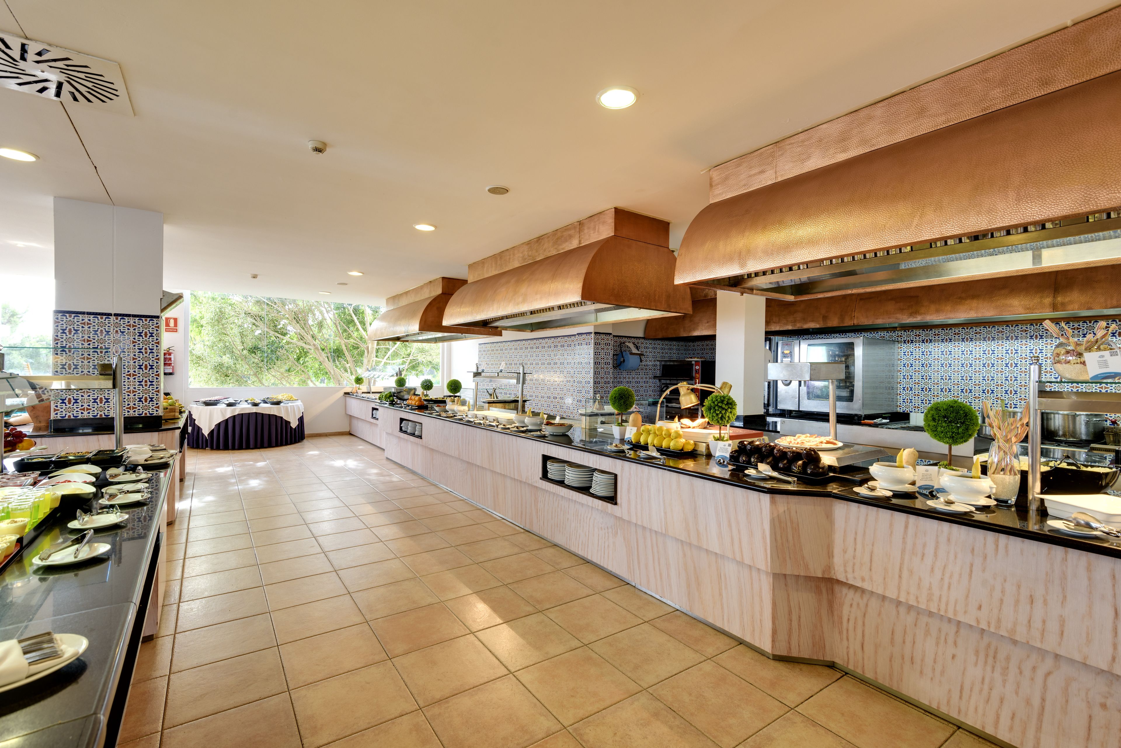 Una presentación de buffet moderna con una mesa larga, diferentes opciones de comida y un revestimiento de azulejos.