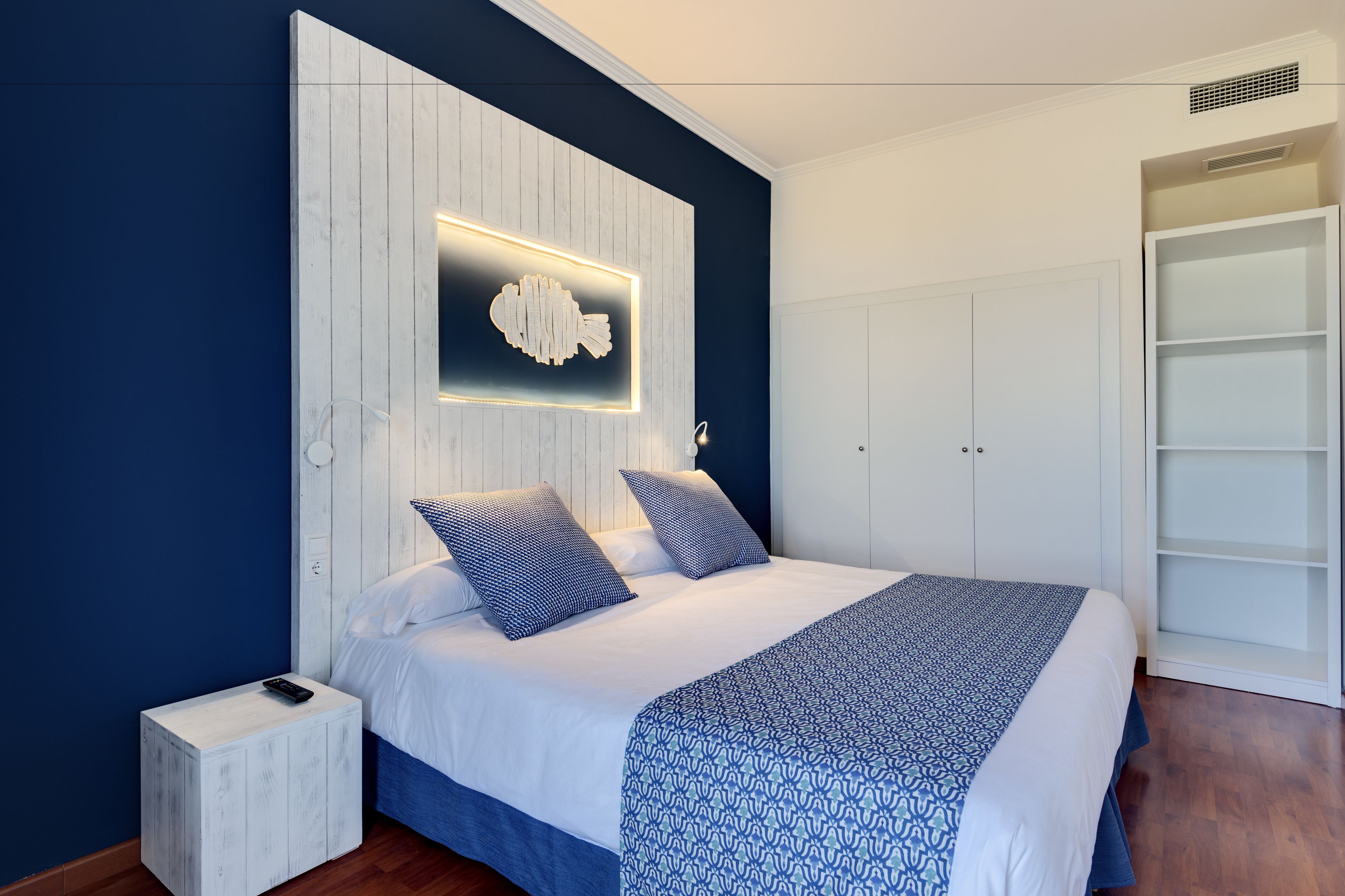 A modern bedroom with a bed, nightstand, and built-in wardrobe.