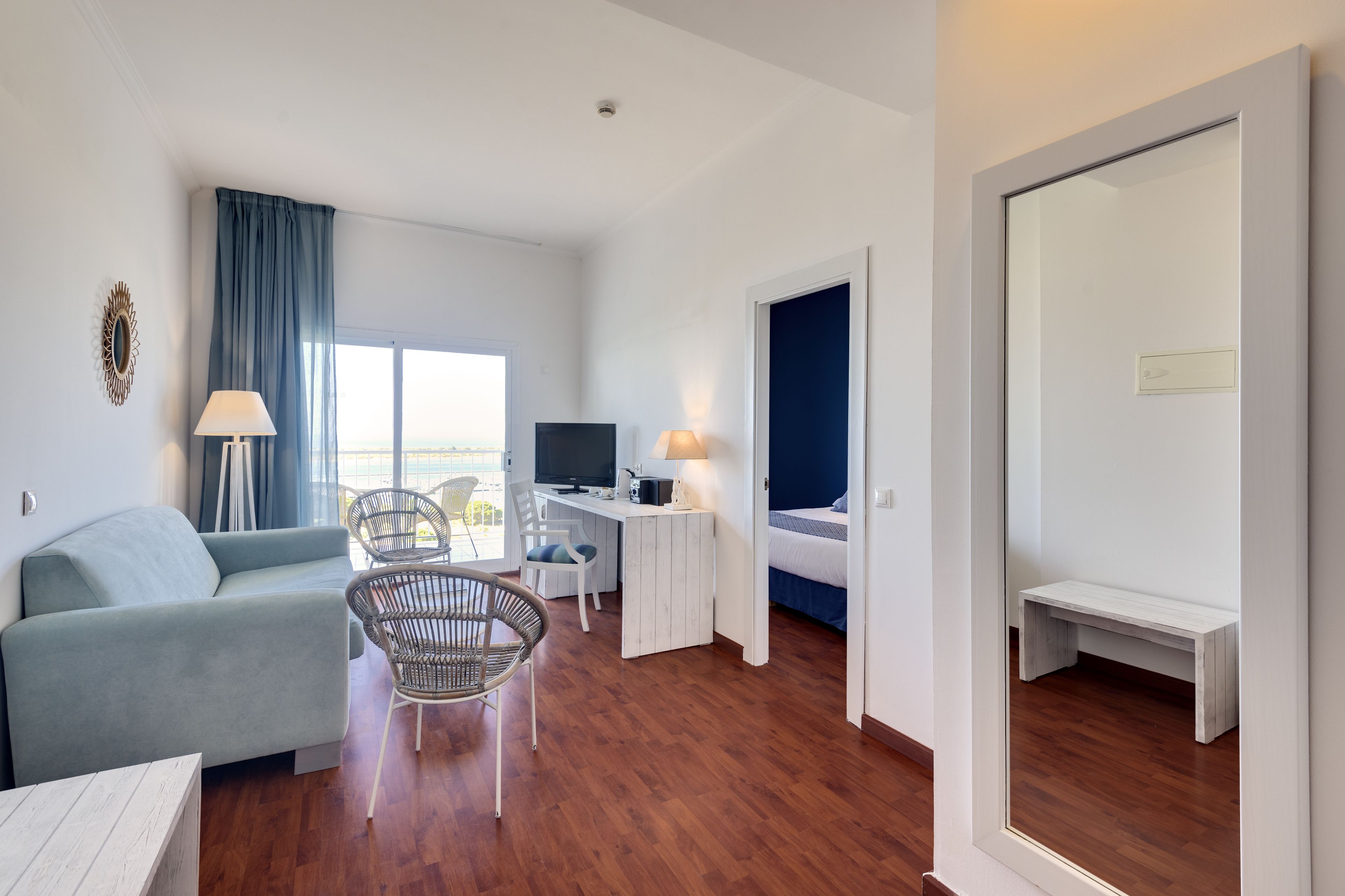 Una habitación de hotel moderna con sofá, mesa de comedor, televisor y escritorio.