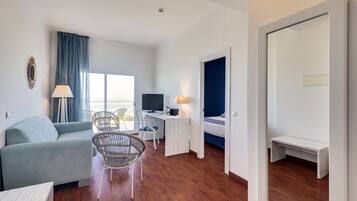 Una habitación de hotel moderna con sofá, mesa de comedor, televisor y escritorio.