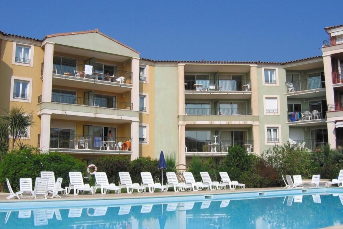 Un hotel con piscina, varios balcones y sillones de descanso.