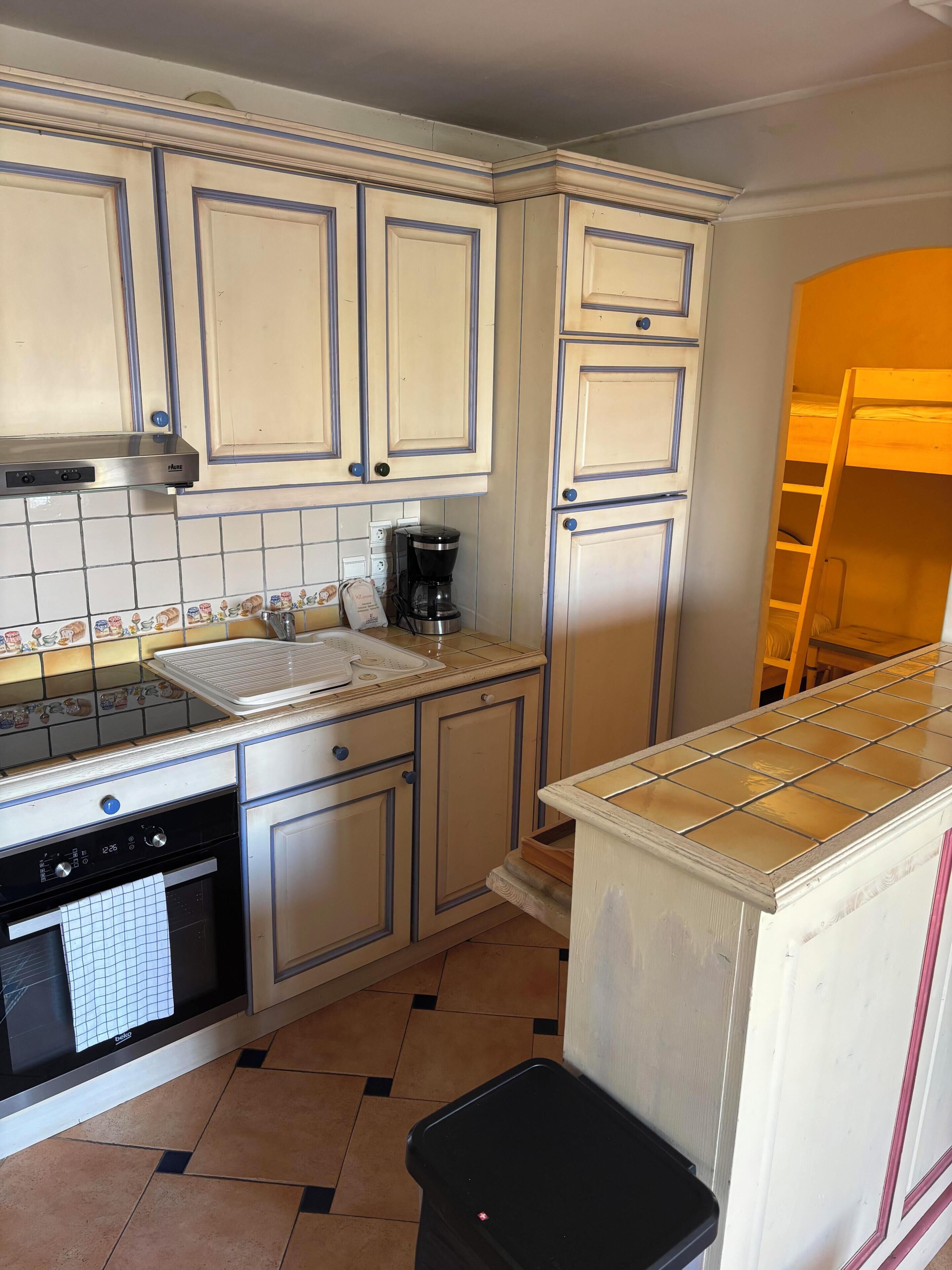 A kitchen with white cabinets, a coffee maker, a sink, and a dishwasher.