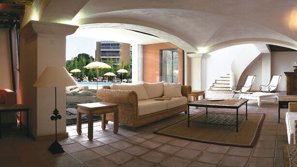 A spacious living area with a sofa, armchairs, and a coffee table. There is a view of an outdoor pool area with umbrellas. - Lagrange Vacances Port Marine (Sainte-Maxime)