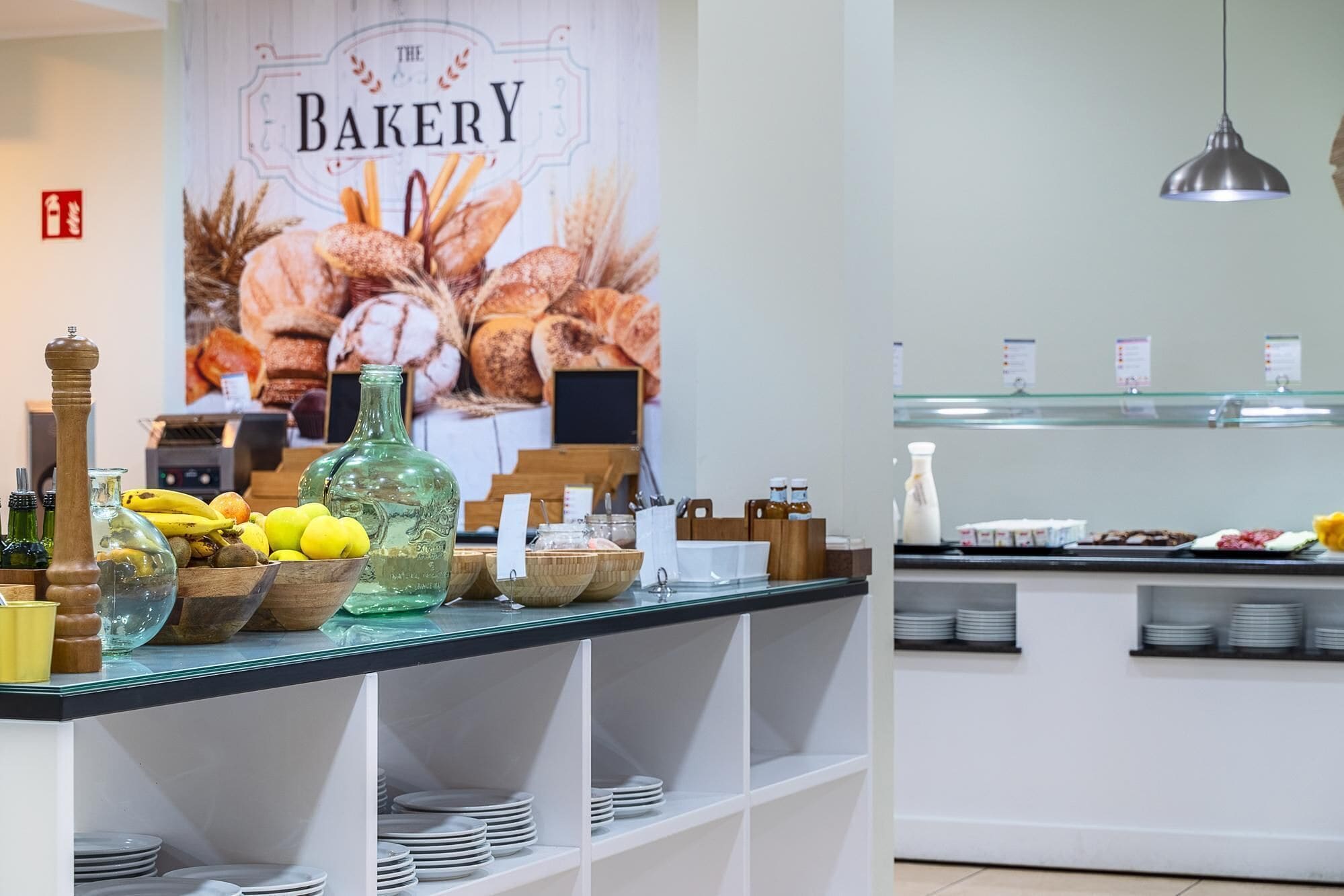 A bakery counter with various baked goods, a green bottle, and a sign reading "The Bakery".