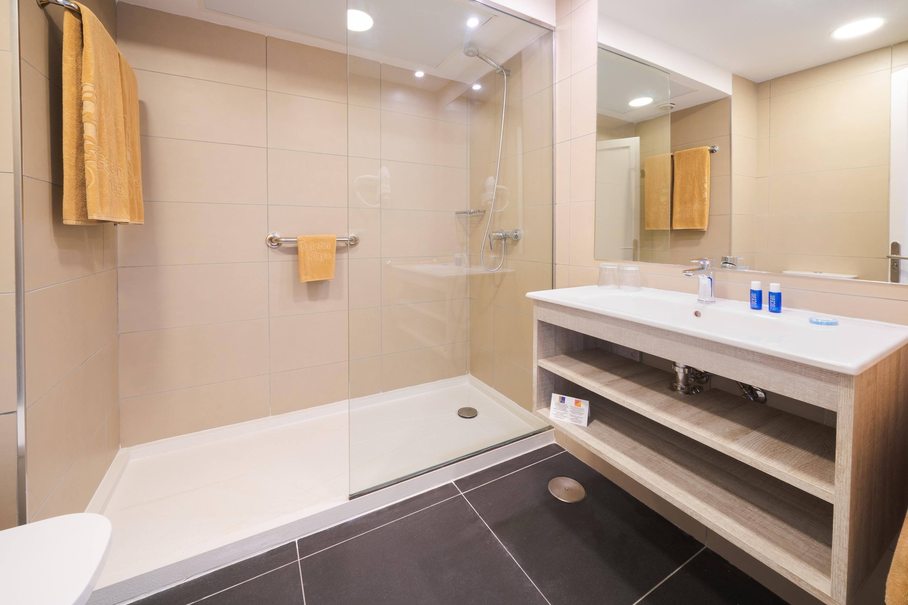 Un bagno moderno con doccia vetrata, un lavandino bianco con mobile contenitore in legno e uno specchio grande.