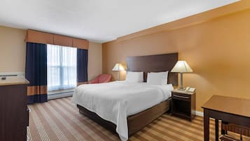 A hotel room with a large bed, two bedside lamps, a desk, and a chair.